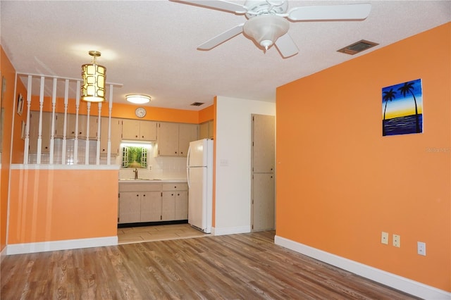 kitchen featuring decorative backsplash, white refrigerator, light hardwood / wood-style floors, and a textured ceiling