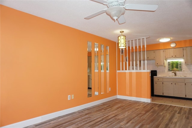 interior space with backsplash, a textured ceiling, ceiling fan, sink, and hardwood / wood-style floors