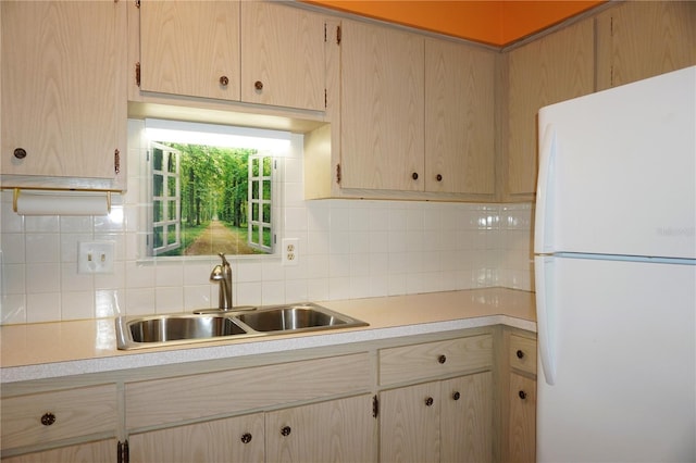 kitchen with decorative backsplash, white refrigerator, sink, and light brown cabinetry