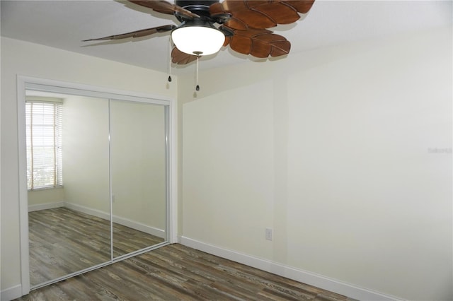 unfurnished bedroom with ceiling fan, dark wood-type flooring, and a closet