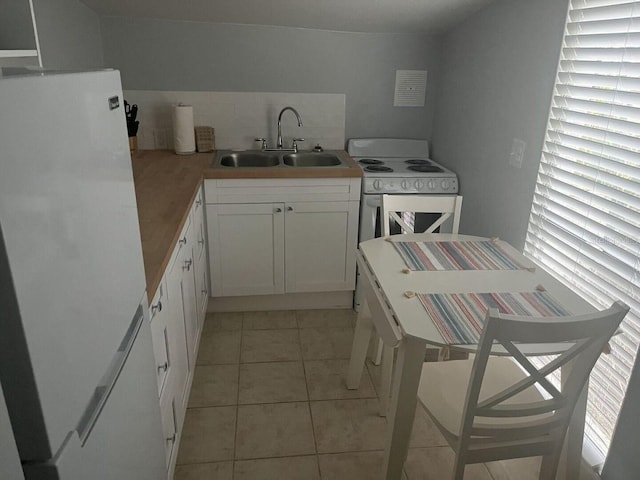 kitchen featuring tasteful backsplash, white appliances, sink, white cabinets, and light tile patterned flooring