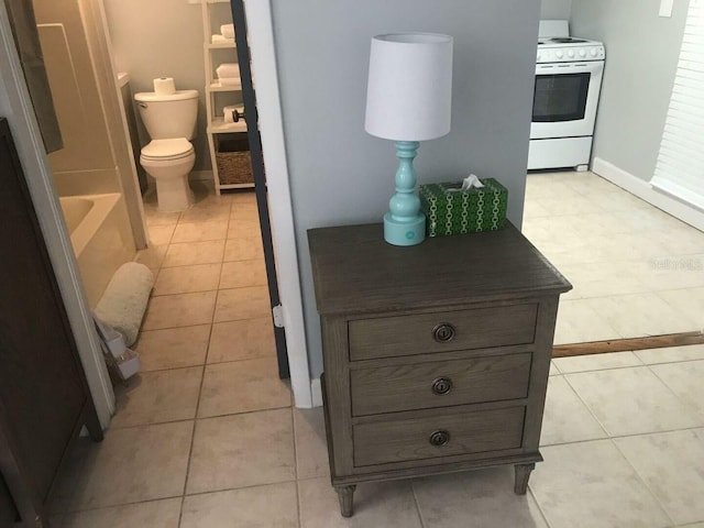 bathroom featuring tile patterned flooring, toilet, and a bathtub