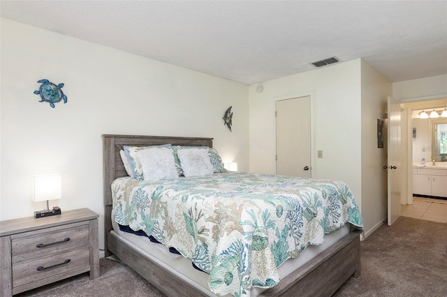 bedroom featuring connected bathroom, sink, carpet, and a textured ceiling