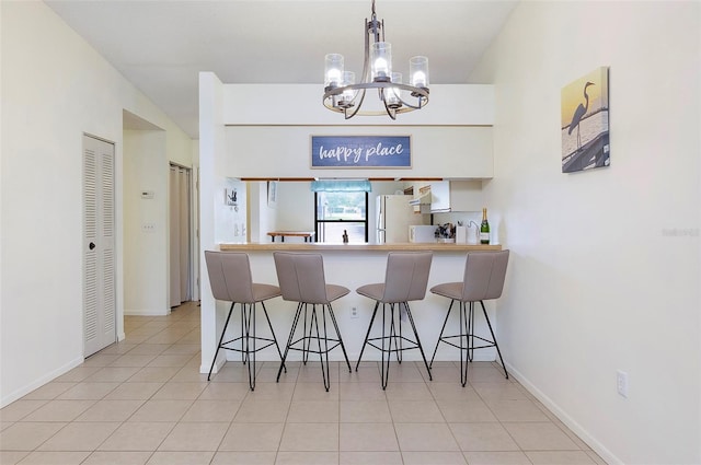 kitchen with a kitchen bar, white cabinetry, hanging light fixtures, and white refrigerator