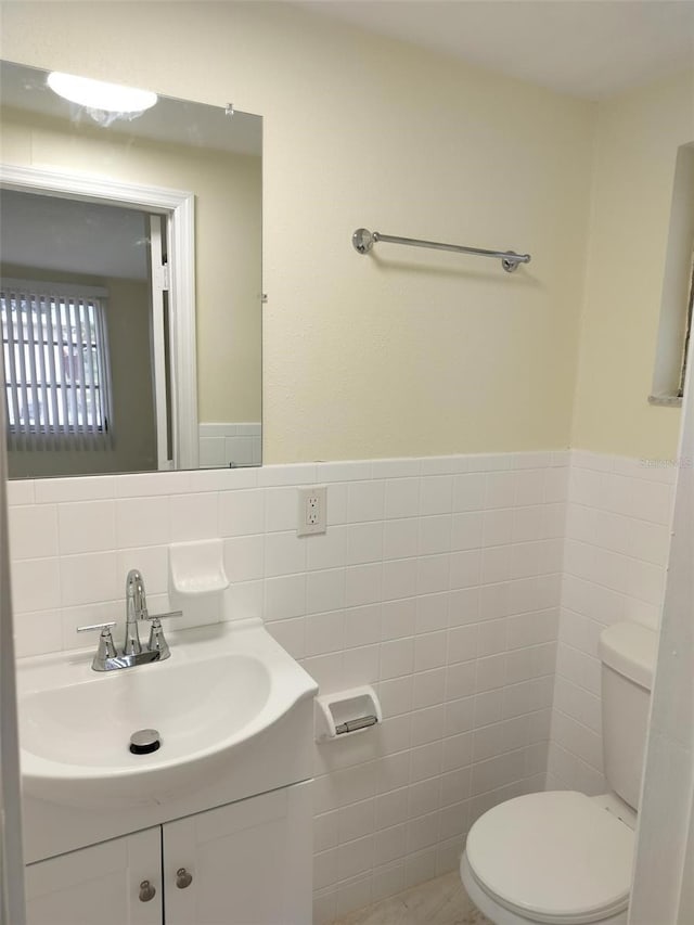 bathroom with tile walls, vanity, and toilet