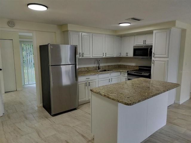 kitchen with sink, a center island, stone counters, stainless steel appliances, and white cabinets