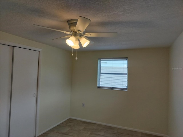 unfurnished bedroom with a textured ceiling, ceiling fan, and a closet