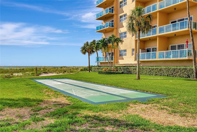 view of property's community featuring shuffleboard and a lawn