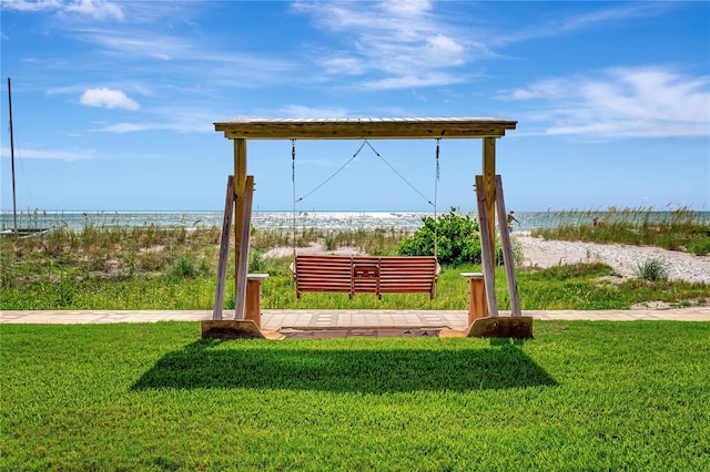 surrounding community with a beach view, a water view, and a lawn