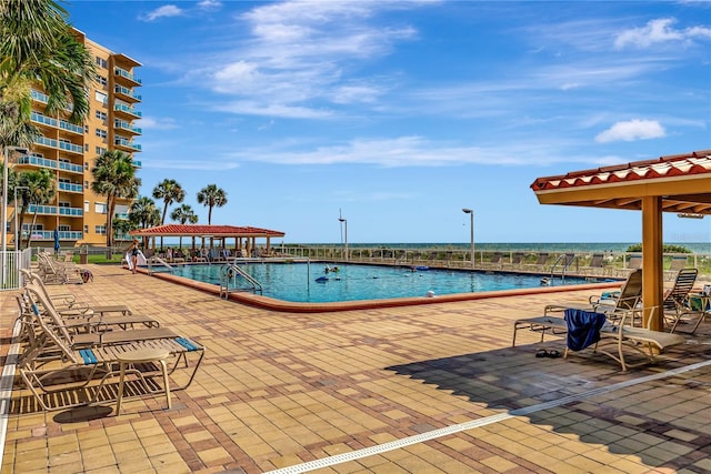 pool featuring a water view and a patio area