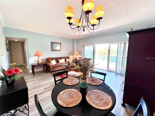 dining room featuring a textured ceiling, light wood-type flooring, an inviting chandelier, and ornamental molding