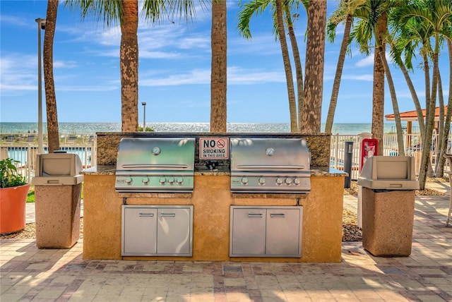 view of patio featuring a water view, an outdoor kitchen, and area for grilling