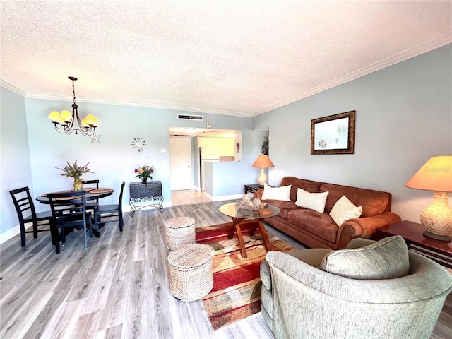 living area featuring light wood finished floors, ornamental molding, a textured ceiling, a chandelier, and baseboards