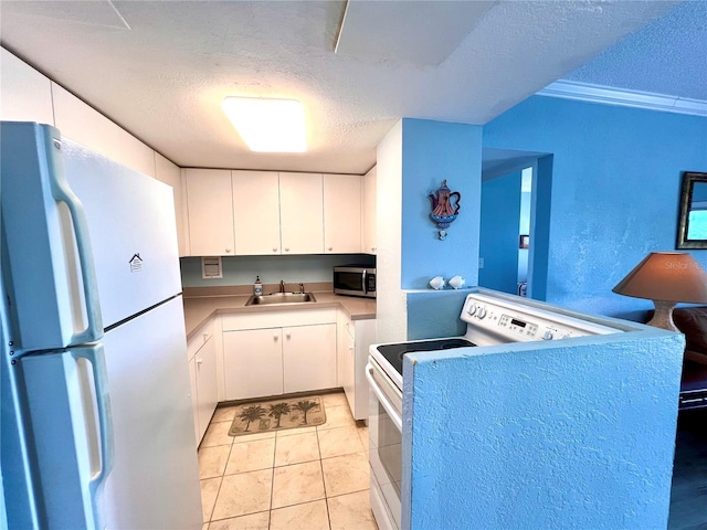 kitchen with white refrigerator, white cabinetry, a textured ceiling, and range