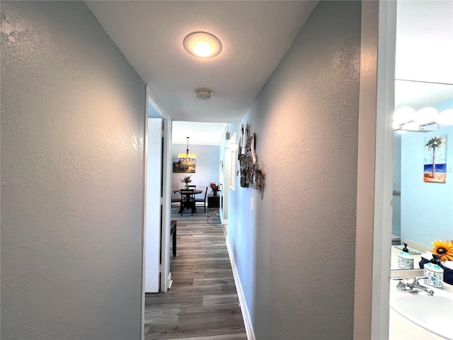 corridor featuring dark wood-style floors, baseboards, and a textured wall