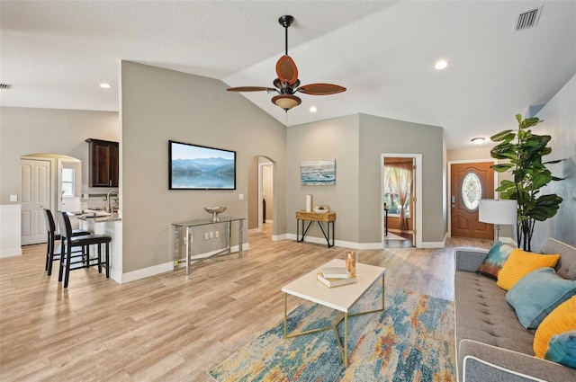 living room with ceiling fan, plenty of natural light, lofted ceiling, and light wood-type flooring