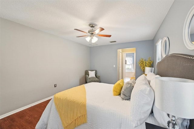 bedroom with hardwood / wood-style flooring, ceiling fan, a textured ceiling, and connected bathroom