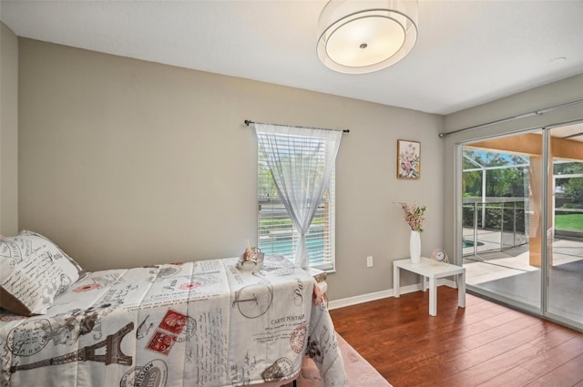 bedroom featuring hardwood / wood-style floors, access to outside, and multiple windows