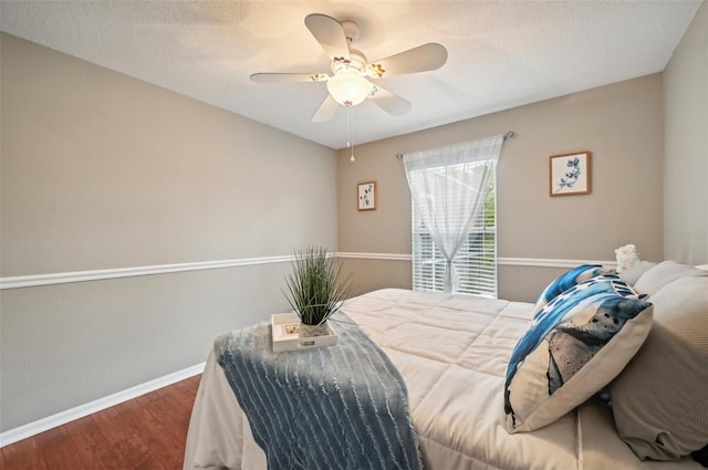 bedroom featuring ceiling fan, wood-type flooring, and a textured ceiling