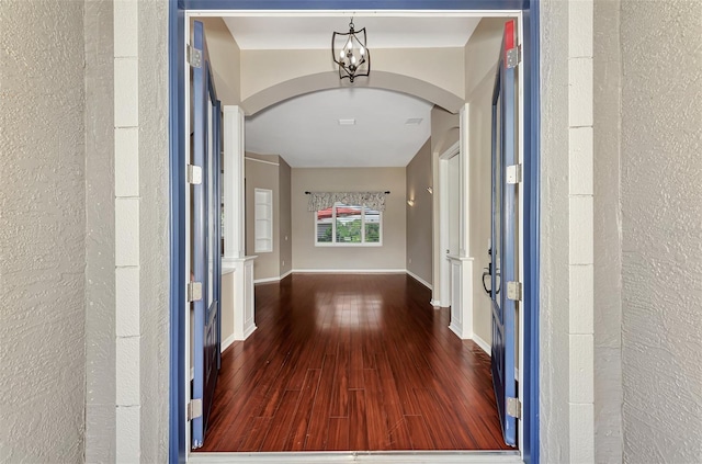 hallway featuring dark wood-type flooring and a notable chandelier