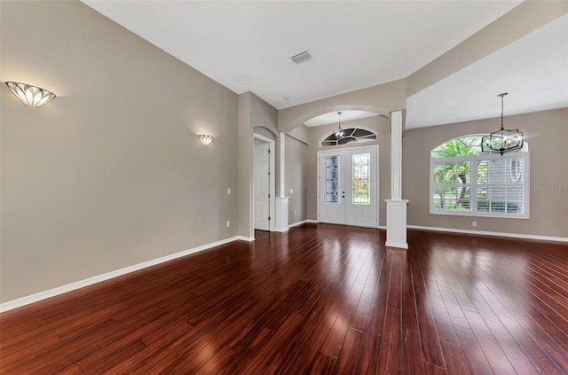 interior space featuring french doors, dark hardwood / wood-style flooring, ornate columns, and a notable chandelier