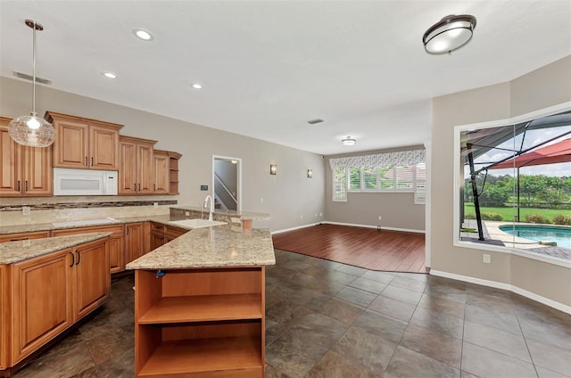 kitchen with tasteful backsplash, light stone counters, dark tile patterned floors, sink, and pendant lighting