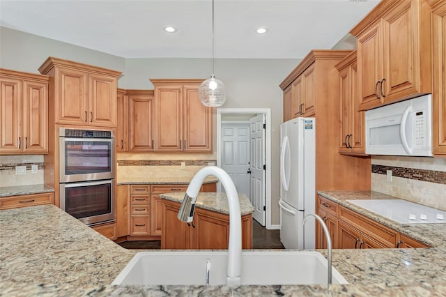 kitchen with pendant lighting, white appliances, backsplash, and sink