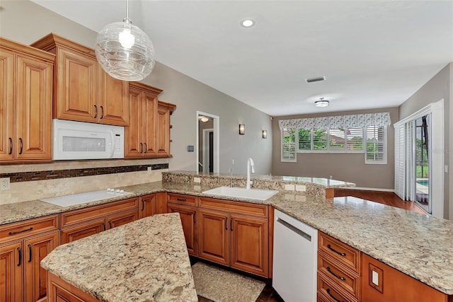 kitchen with sink, light stone counters, pendant lighting, white appliances, and decorative backsplash