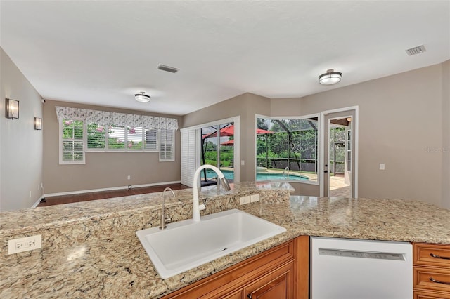 kitchen with light stone counters, sink, white dishwasher, and hardwood / wood-style flooring