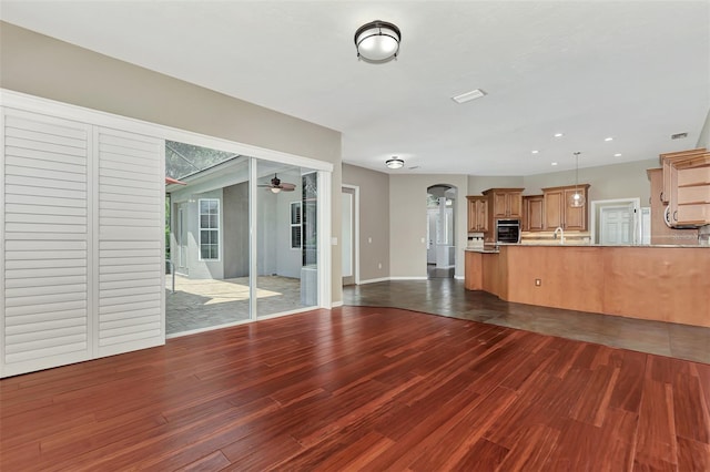 unfurnished living room featuring ceiling fan and dark hardwood / wood-style flooring