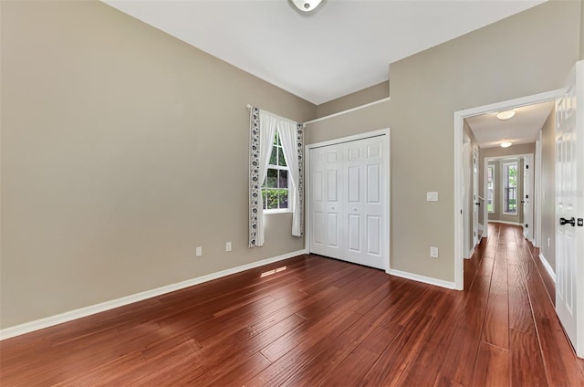 unfurnished bedroom featuring dark wood-type flooring, multiple windows, and a closet