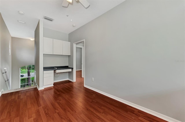 unfurnished living room featuring ceiling fan, dark hardwood / wood-style flooring, and built in desk