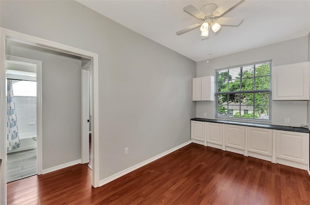 interior space featuring ceiling fan, white cabinets, and dark wood-type flooring