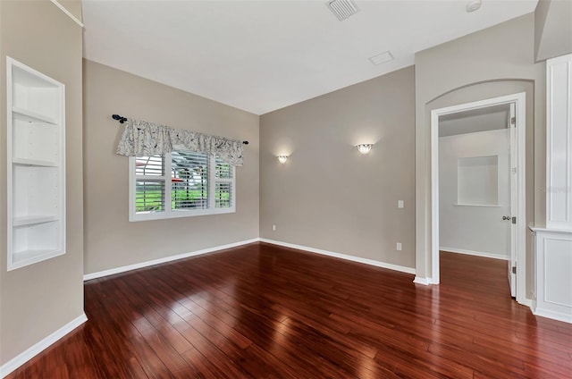 empty room featuring dark hardwood / wood-style floors and built in features