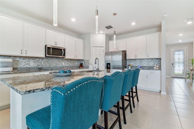 kitchen with appliances with stainless steel finishes, tasteful backsplash, a breakfast bar, and a kitchen island with sink