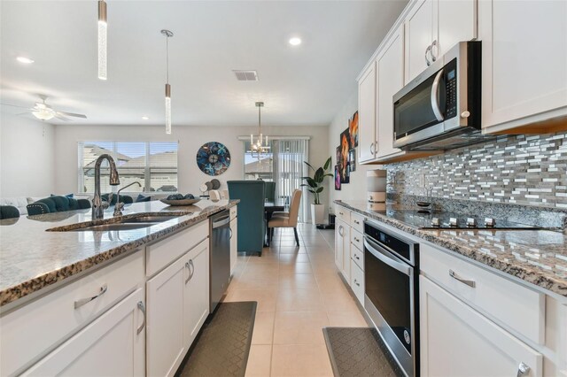 kitchen with ceiling fan, stainless steel appliances, backsplash, light tile floors, and white cabinets