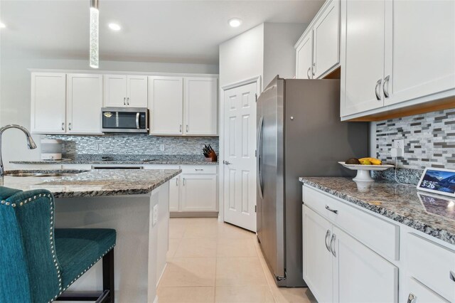 kitchen with white cabinets, light tile flooring, stainless steel appliances, backsplash, and sink