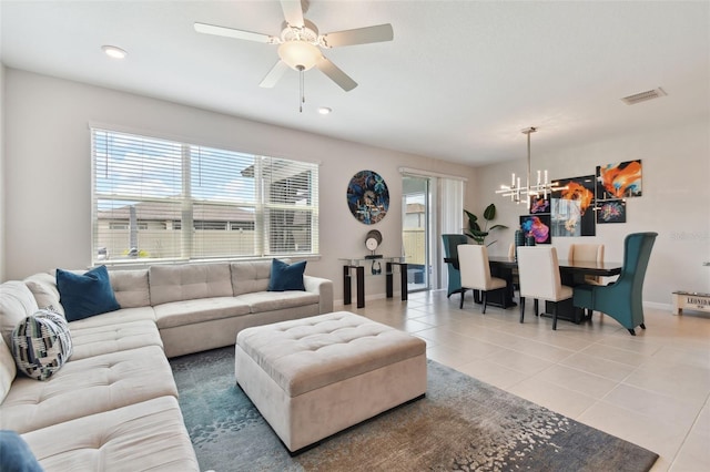 tiled living room featuring ceiling fan with notable chandelier