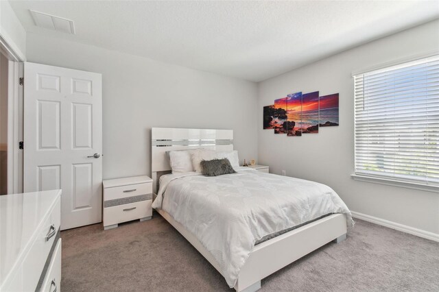 bedroom with light colored carpet and multiple windows