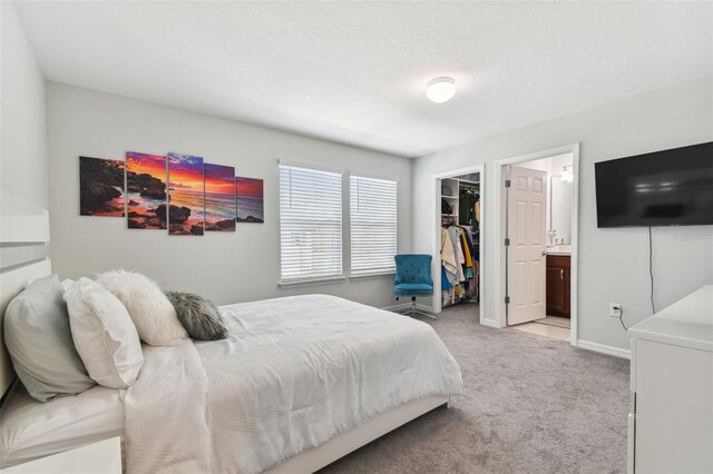 bedroom featuring ensuite bath, a closet, light carpet, and a spacious closet