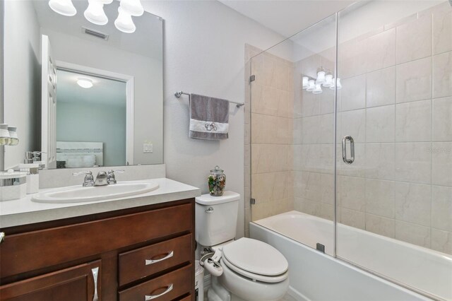 full bathroom featuring combined bath / shower with glass door, toilet, and large vanity