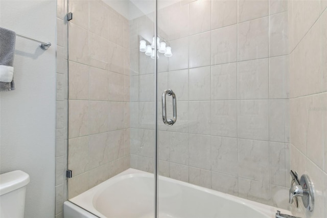 bathroom with combined bath / shower with glass door and toilet