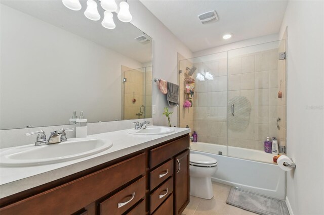 full bathroom featuring double vanity, tile flooring, bath / shower combo with glass door, and toilet