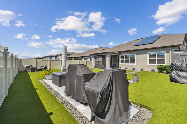 rear view of house with solar panels and a lawn