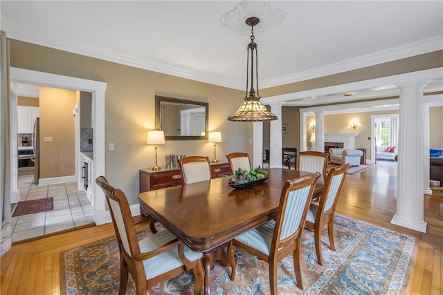 dining room featuring decorative columns, crown molding, and light hardwood / wood-style flooring