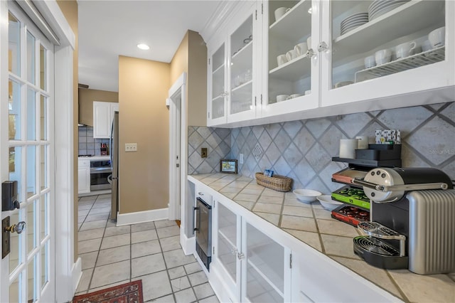 kitchen featuring backsplash, tile countertops, light tile patterned floors, and white cabinets