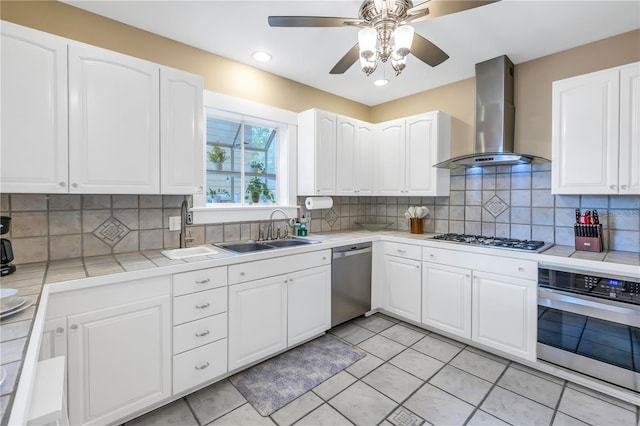 kitchen featuring sink, white cabinetry, stainless steel appliances, decorative backsplash, and wall chimney exhaust hood