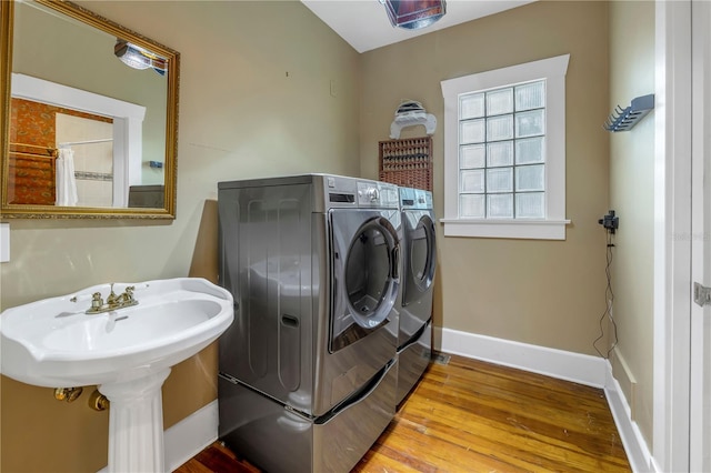 clothes washing area with independent washer and dryer and light wood-type flooring