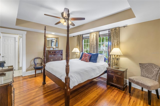 bedroom featuring wood-type flooring, a raised ceiling, and ceiling fan