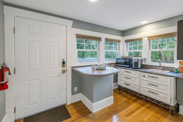 kitchen with sink, white cabinets, and light wood-type flooring